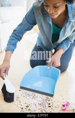 African American woman sweeping up confetti Stock Photo