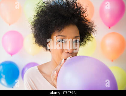 African American woman blowing up balloon for party Stock Photo