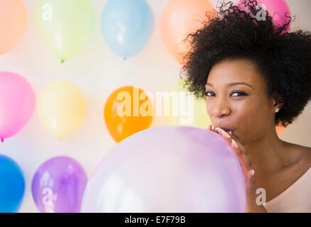 African American woman blowing up balloon for party Stock Photo