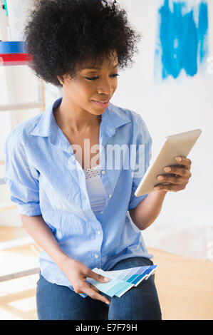 African American woman using tablet computer to select paint color Stock Photo