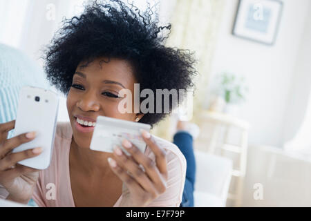 African American woman shopping on cell phone Stock Photo