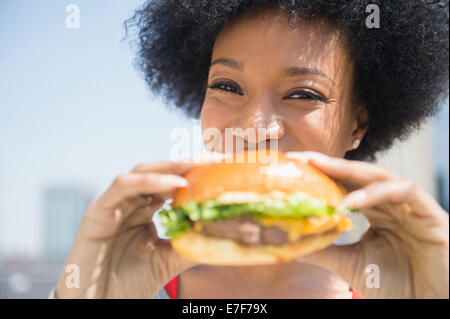 African American woman eating cheeseburger Stock Photo