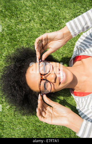 African American woman laying in grass wearing eyeglasses Stock Photo