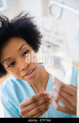 African American nurse connecting intravenous bag Stock Photo