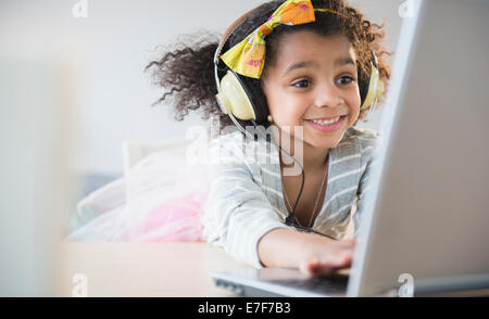 African American girl listening to headphones and using laptop Stock Photo