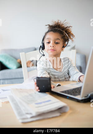 African American girl using headset, cell phone and laptop Stock Photo