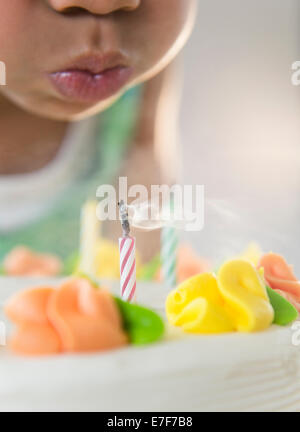 African American girl blowing out candles on birthday cake Stock Photo
