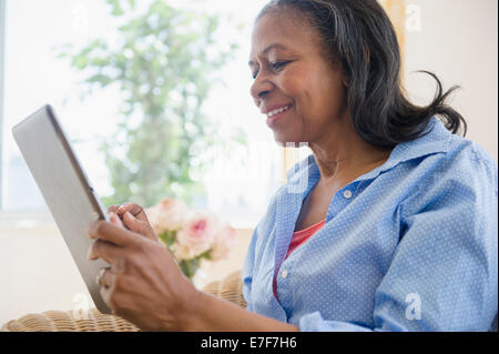 Mixed race woman using tablet computer on sofa Stock Photo