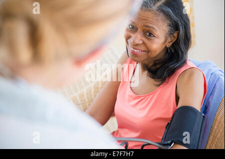 Woman having blood pressure taken on sofa Stock Photo