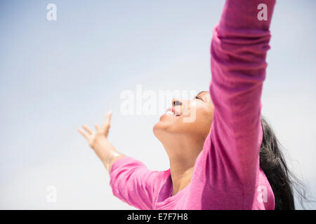 Mixed race woman with arms outstretched outdoors Stock Photo