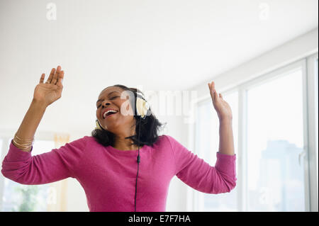 Mixed race woman listening to headphones in living room Stock Photo