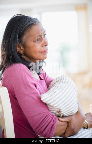 Sad mixed race woman hugging pillow Stock Photo