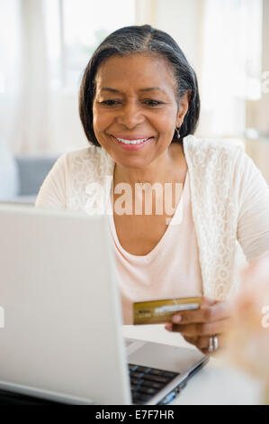 Mixed race woman shopping on laptop Stock Photo