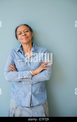 Mixed race woman standing with arms crossed Stock Photo