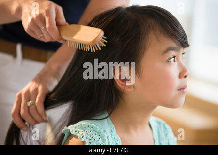 Mother brushing daughter's hair Stock Photo