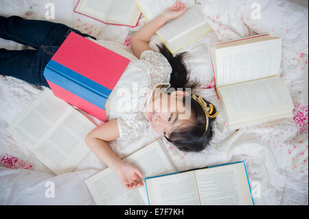 Filipino girl laying in bed with books Stock Photo