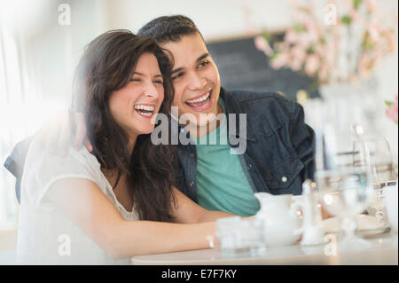 Hispanic couple laughing in cafe Stock Photo