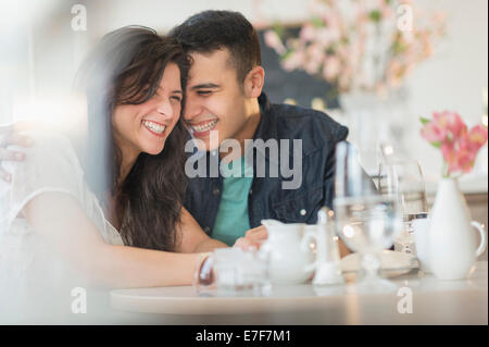 Hispanic couple laughing in cafe Stock Photo