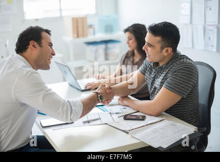 Hispanic businessmen shaking hands in office Stock Photo