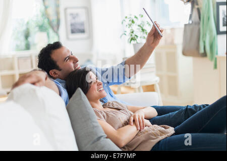 Hispanic couple using tablet computer on sofa Stock Photo