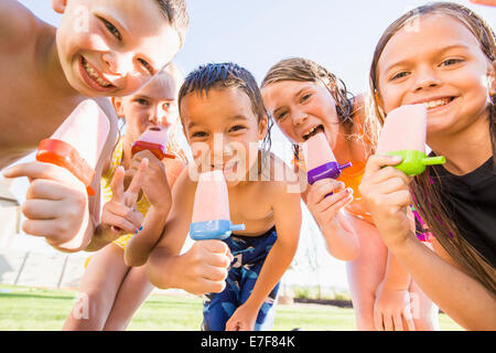 Caucasian children eating popsicles outdoors Stock Photo