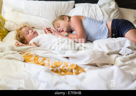 Caucasian girl and toddler brother asleep on bed Stock Photo