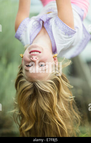 Caucasian girl hanging upside down outdoors Stock Photo