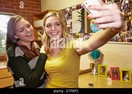 Caucasian students taking pictures in dorm room Stock Photo