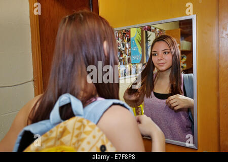 Caucasian student brushing hair in dorm room Stock Photo