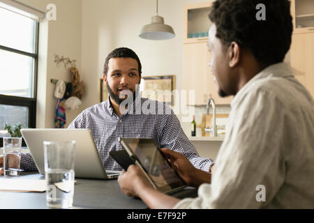 Friends using technology at breakfast table Stock Photo