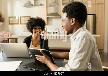 Couple using technology at breakfast table Stock Photo