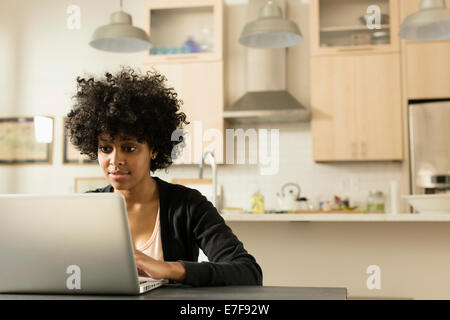 Mixed race woman using laptop at breakfast table Stock Photo