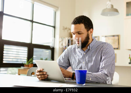Mixed race businessman using tablet computer at desk Stock Photo