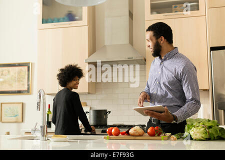 Mixed race couple cooking together in kitchen Stock Photo