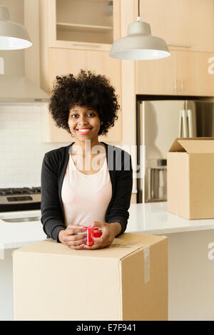 Mixed race woman drinking coffee in new house Stock Photo