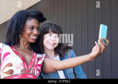 Women taking cell phone picture together outdoors