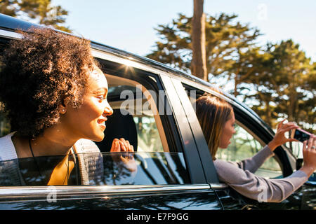Women taking cell phone picture together in car