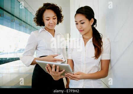 Businesswomen using tablet computer in lobby Stock Photo