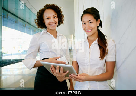 Businesswomen using tablet computer in lobby Stock Photo