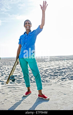 Older Black woman holding skateboard on beach Stock Photo