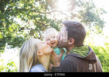 Caucasian couple kissing baby in backyard Stock Photo