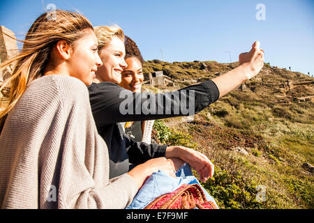 Women taking cell phone picture together on rural hillside