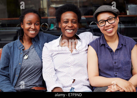 Women smiling outside coffee shop on city street Stock Photo