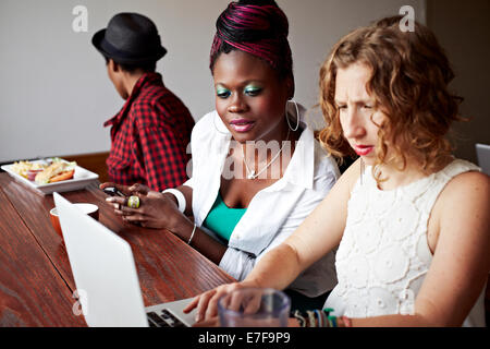 Women using laptop together in cafe Stock Photo