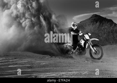 Caucasian man riding dirt bike in dust cloud Stock Photo
