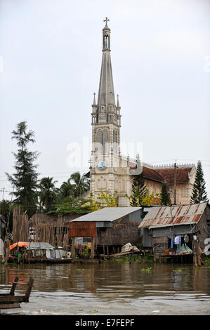 Shacks and 19th Century Catholic cathedral on the Mekong River, Cai Be, Tien Giang Province, Vietnam Stock Photo