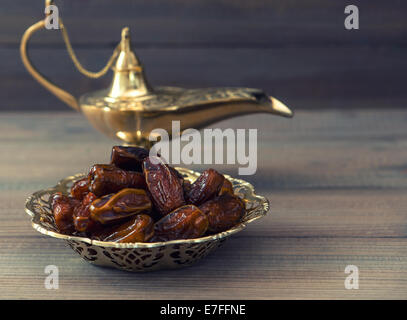 Dates and golden arabic lantern on wooden background. Oriental food. Retro style toned picture Stock Photo