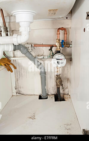 a water meter under a domestic sink with moldy walls the uk these meters have radio signals for collecting readings for Severn Stock Photo