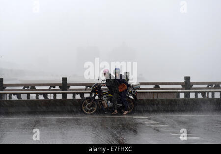 Fangchenggang, China's Guangxi Zhuang Autonomous Region. 16th Sep, 2014. People ride a motorcycle against rain in Fangchenggang City, south China's Guangxi Zhuang Autonomous Region, Sept. 16, 2014. The fifteenth Typhoon Kaimaegi hit Guangxi on Tuesday, affecting about 294,700 local residents and forcing the relocation of 25,800 people. Credit:  Lu Boan/Xinhua/Alamy Live News Stock Photo