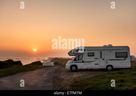 Motorhomes parked in car park for RVs / recreational vehicle along the coast at sunset with view over the sea Stock Photo